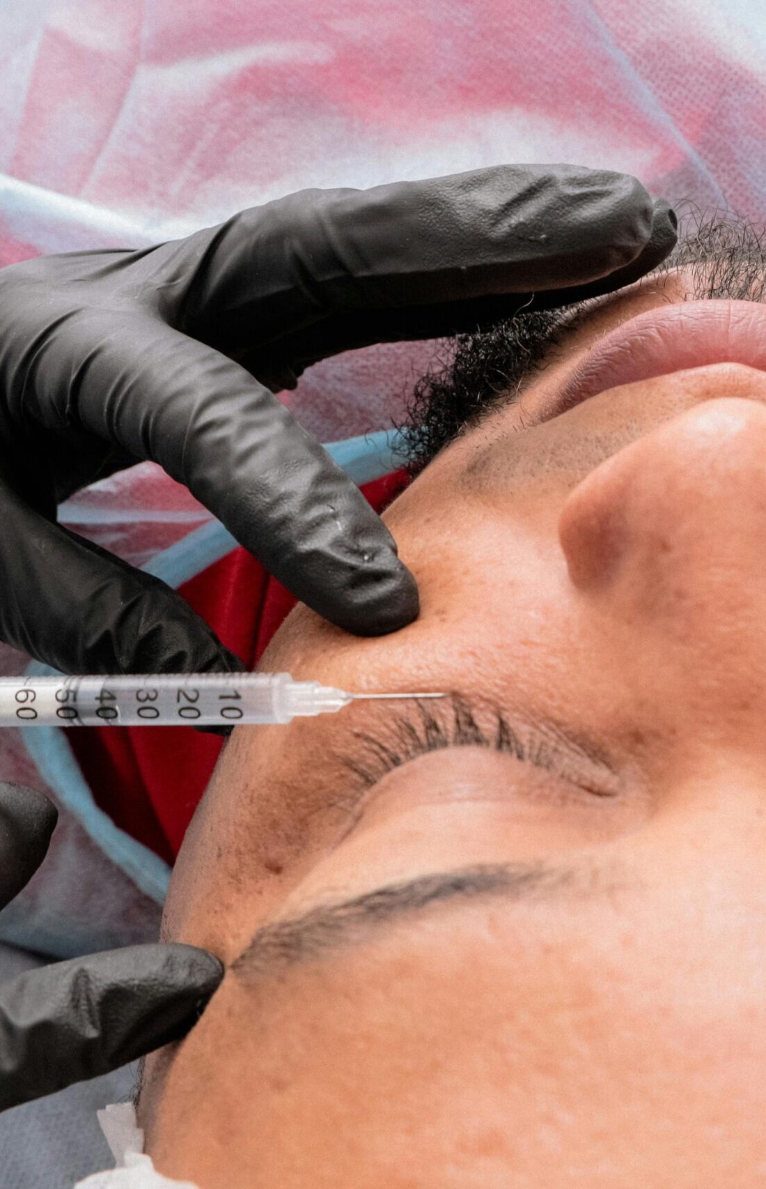 Man receiving facial treatment with syringe in medical facility.